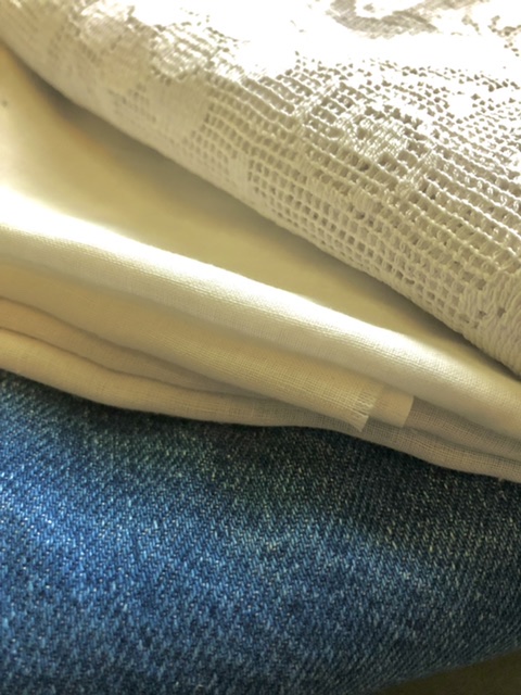 Image shows denim, linen and lace fabric bolts