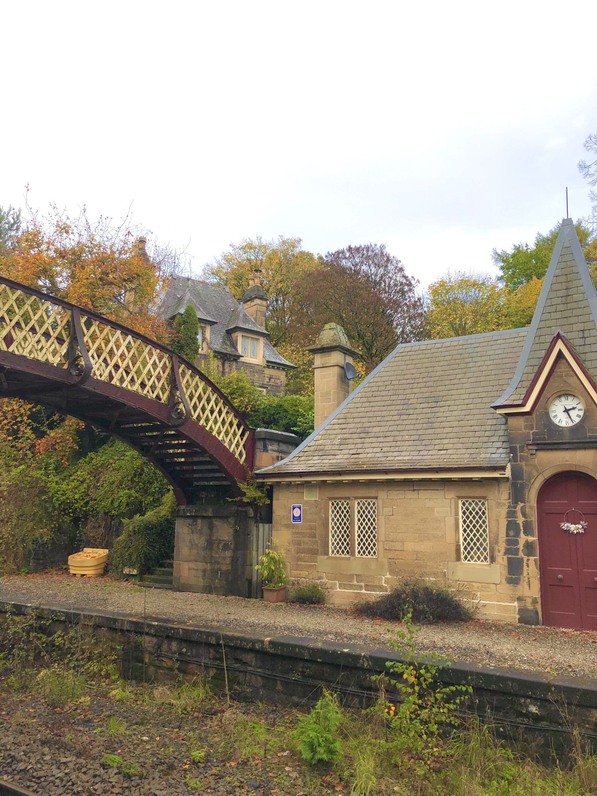 Image shows the disused platform of Cromford Railway Station, and part of the ironwork bridge crossing the tracks. The clock of the old platform is still working. The space is now used as a holiday flat.